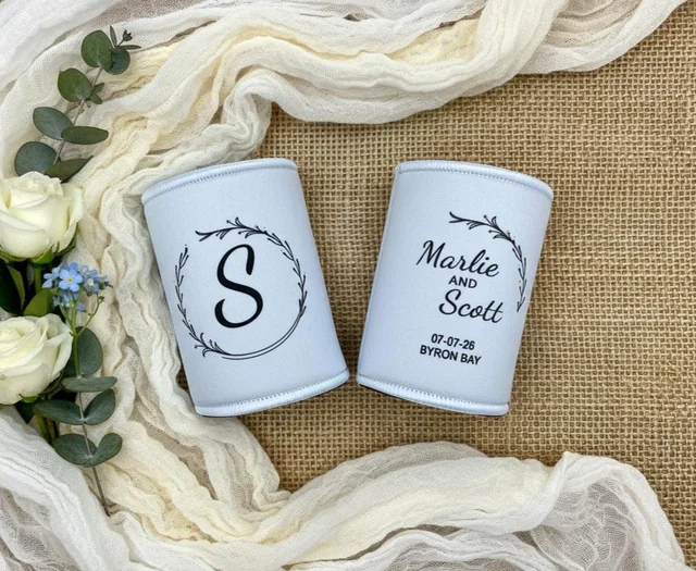 Pale blue personalised stubby holders with a botanical monogram and Marlie and Scott’s wedding details